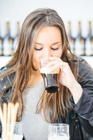 Portrait of beautiful brunette drinking dark craft beerの写真素材