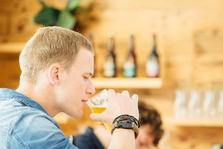 Side view of handsome blond man drinking craft beer.Bokehの写真素材