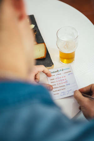 Overshoulder view on mans hands writing rate of beer on list of paperの写真素材