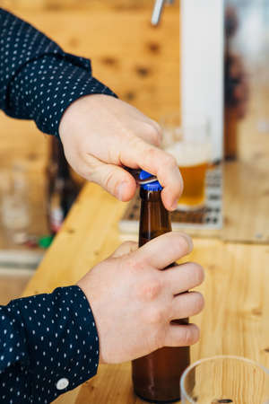 Close-up of unrecognizable man opening bottle of beer