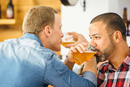 Two handsome men drinking light beer with crossed armsの写真素材