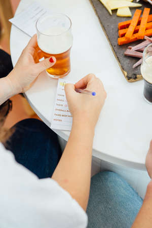 Close-up of unrecognizable woman writing on rating list of beer.from aboveの写真素材