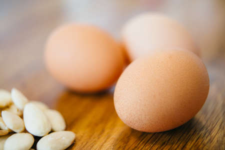 Three raw eggs on table with peeled almondの写真素材