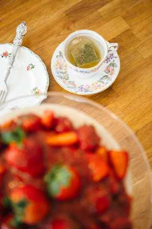 Close up of cup of tea with unfocused cake on foreground