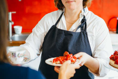 Close-up of unrecognizable confectioner giving drink and strawberry cake to customerの写真素材