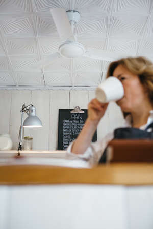 Unfocused woman drinking coffee against of board with menuの写真素材