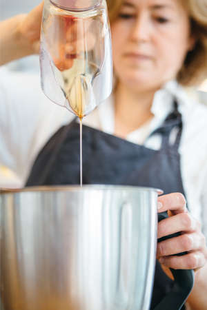 Close up of confectioner pouring honey in bowl from pitcherの写真素材