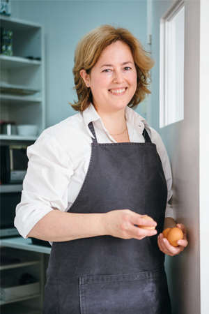 Portrait of happy adult woman with raw eggs smiling at cameraの写真素材