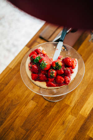 Close-up of cut tasty cake with strawberry on cakestand with knifeの写真素材