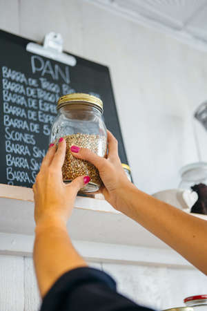 Unrecognizable woman putting buckwheat on shelfの写真素材