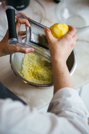 Close-up of unrecognizable woman grating lemon peel in bowlの写真素材