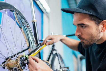 Bearded craftsman taking measurements of bicycle