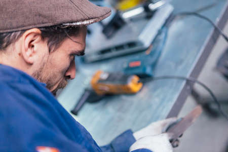 Side view of bearded man working with metal detailの写真素材