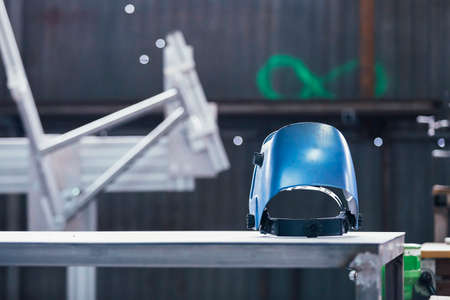 Close-up of plastic protective mask on iron table against of metal wallの写真素材