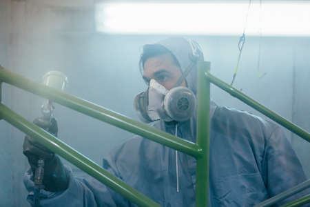 Dark-haired craftsman painting bikes frame in greenの写真素材