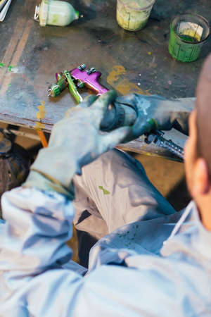 Close-up of unrecognizable man twisting paint gun. Painted detail on tableの写真素材