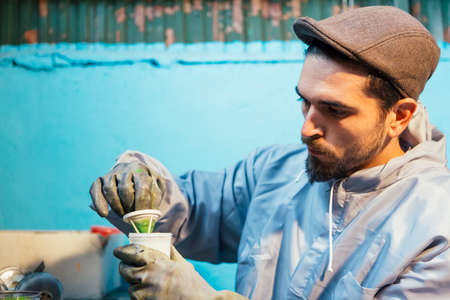Bearded craftsman preparing green paint for bike frame