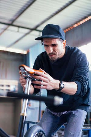 Close-up of craftsman in black cap squinting at bicycle seatの写真素材