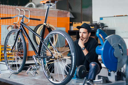 Bearded craftsman thoughtfully looking at bicycleの写真素材