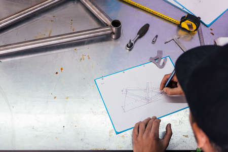 Professional craftsman drawing bicycle on metal table. Overhead.の写真素材
