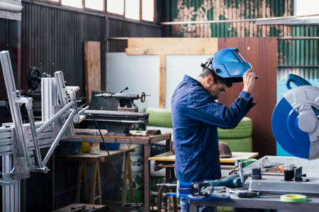 Professional craftsman putting on mask for welding metalの写真素材