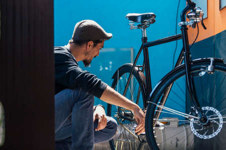 Bearded man in cap looking at his bikeの写真素材