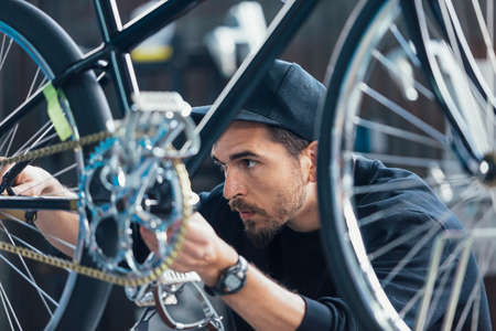 Close-up of professionl constructor of bicycles looking at chainの写真素材
