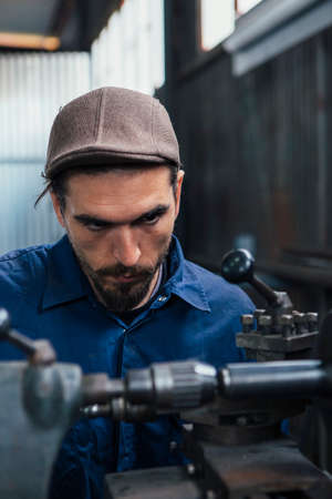 Close-up of bearded constructor looking attentively at working machine