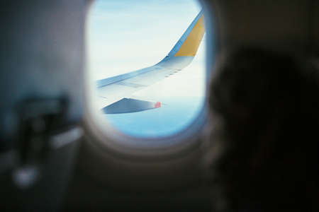 Wing of an aircraft seen through the window from inside an airplaneの写真素材