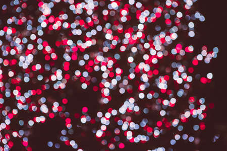 Red and white glitter bokeh lights on a dark background. Useful as an unfocused background. Copy space area availableの写真素材
