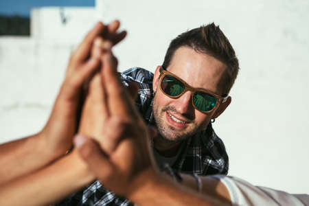 Crop shot of group of people giving high five in sun light. の写真素材