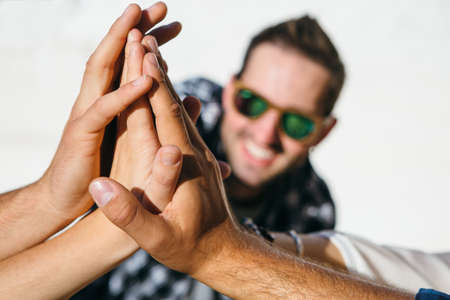 Close up crop shot of people giving high five in sunlight.の写真素材