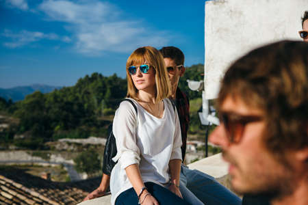 Group of young friends in sunglasses sitting on terrace in sunlight and posing.の写真素材