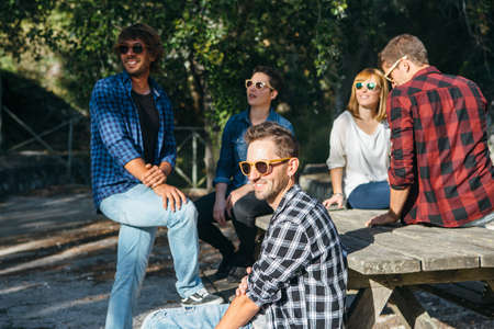Young friends in sunglasses smiling while having rest together in park.の写真素材