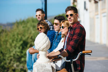 Young trendy people all in sunglasses standing in row on balcony outside.の写真素材