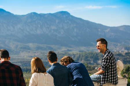 Laughing friends standing on balcony and laughing with mountains on background.の写真素材