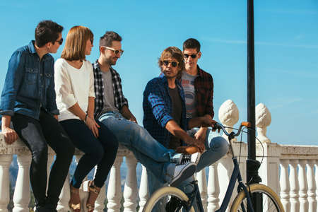 Smiling and trendy friends in sunglasses posing on balcony and having time together.の写真素材