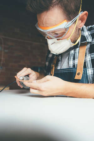 Young worker in protective eyewear and mask polishing rim for glasses.の写真素材