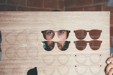 Young woodworker holding blank for glasses and looking through it.の写真素材