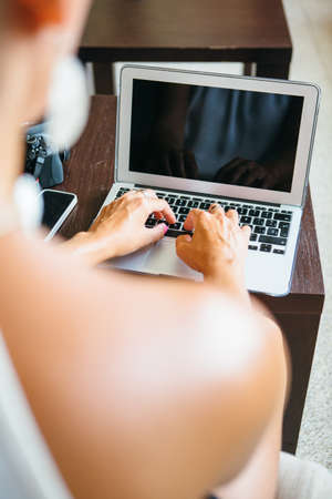 Back view of stylish woman typing at laptop keyboard.の写真素材
