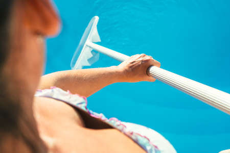 Crop shot from above of woman cleaning pool with net.の写真素材