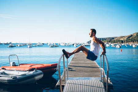 Horizontal outdoors shot of man exercising on handrail of pier.
