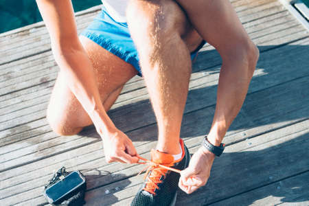 Unrecognizable fit man tightening up the laces of sneakers.の写真素材