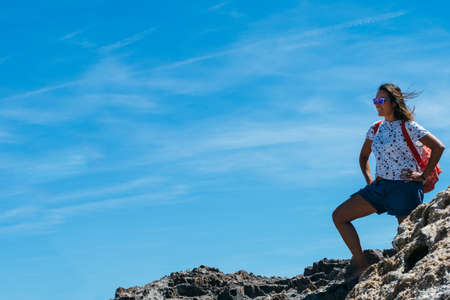 Woman with backpack standing on rock and admiring view.