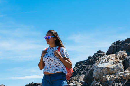 Female tourist with backpack standing on rock and looking away.の写真素材