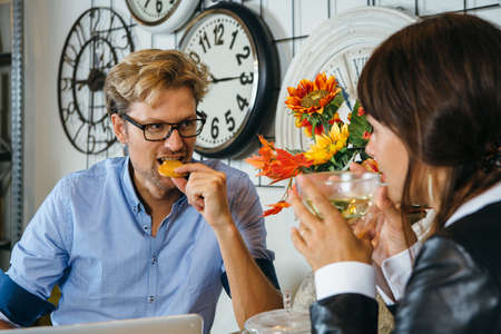 Man eating a cookie while meeting with female partner in cafe.の写真素材