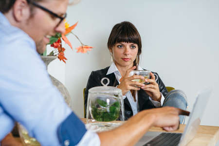 Pretty woman having tea and looking at presentation man showing.の写真素材