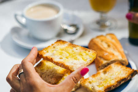 Close-up female hand holding a toasted bread with oil on top.の写真素材