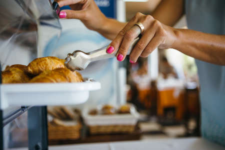 Unrecognizable woman taking croissant from breadbin. Horizontal indoors shot.の写真素材