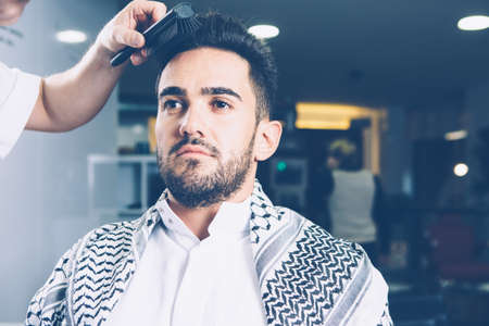 Horizontal indoors shot of hairdresser do hair of a client in barbershop.の写真素材